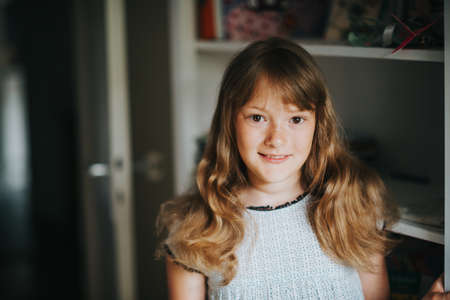 Indoor portrait of adorable kid girl with curly hair and freckles on her faceの写真素材