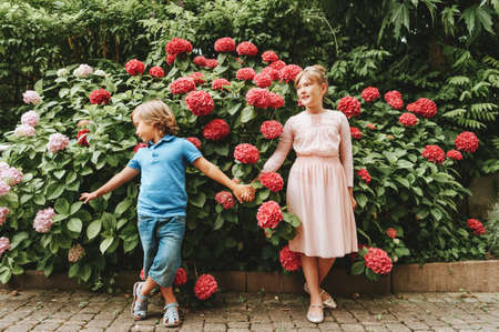 Outdoor portrait of two cute kids playing together in summer garden