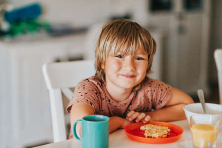 Cute little boy eating his breakfast with waffle and hot chocolateの写真素材