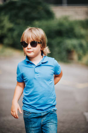 Outdoor portrait of adorable little boy wearing blue polo and fashion sunglassesの写真素材