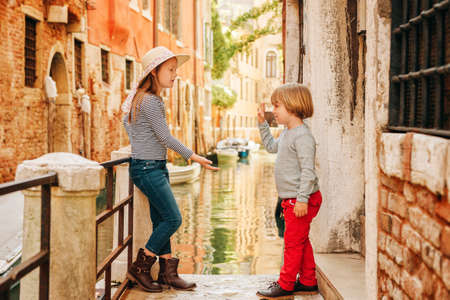 Two kids playing on the bridge in Venice. Little girl and boy visiting Venice, Italy. Small tourists in Europeの写真素材