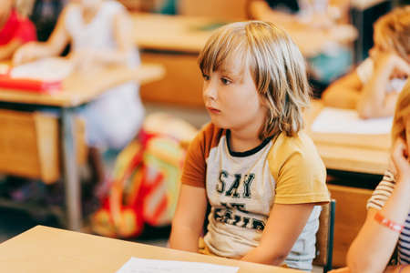 Concentrated little boy listening to the teacher in classroom 