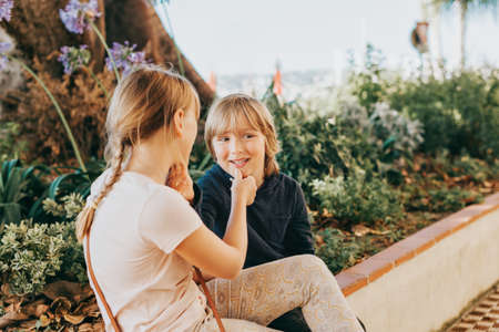 Group of two funny kids playing together outside, small brother and sister having fun outdoorsの写真素材