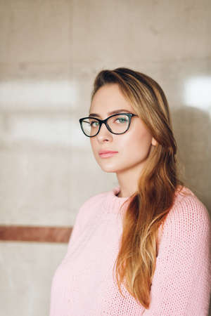 Portrait of young beautiful girl wearing glasses and pink pullover