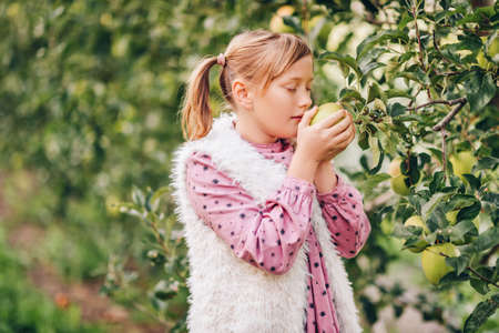 Kid girl playing in apple orchard wearing pink vintage dressの写真素材