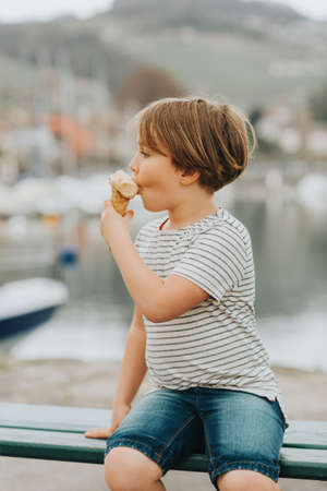 Outdoor portrait of funny little boy eating ice cream on a hot dayの写真素材