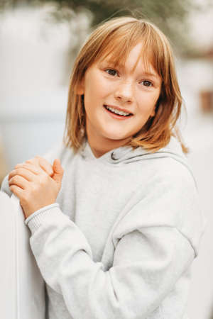 Outdoor portrait of funny little girl wearing grey sweatshirt