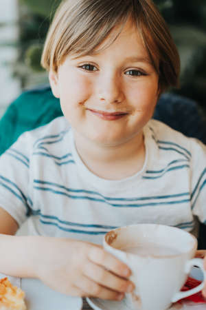 Funny little boy drinking hot chocolate for breakfastの写真素材