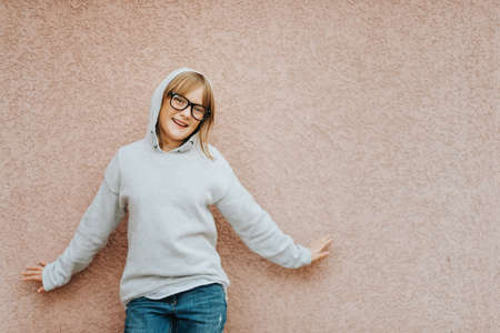 Outdoor portrait of funny little girl wearing grey sweatshirt posing against pink backgroundの写真素材