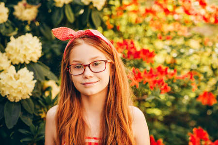 Close up portrait of adorable red-haired kid girl wearing eyeglasses, bright summer imageの写真素材