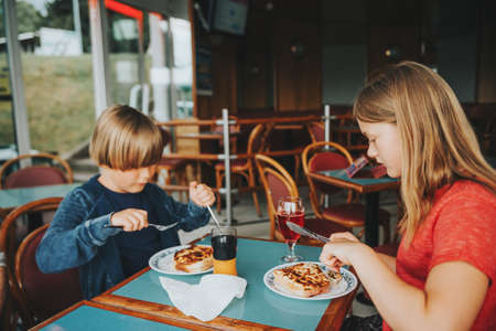 Two children eating Croque-Monsieur in the restaurant, traditional french toast with ham and cheeseの写真素材