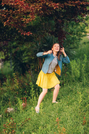 Young kid girl playing with a tree in beautiful garden at sunset lightの写真素材