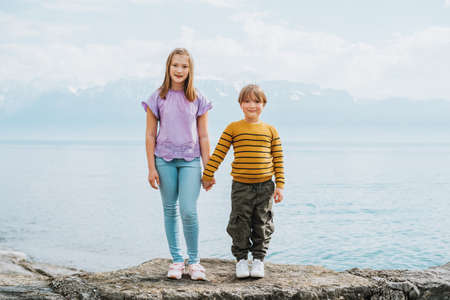Cute kids playing by the lake, holding hands, little brother and sister portraitの写真素材