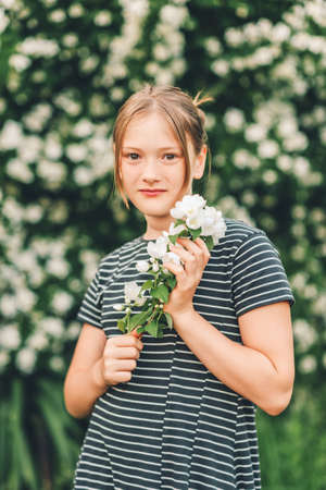 Outdoor portrait of adorable preteen 10 year old girl in beautiful jasmin garden, wearing stripe dressの写真素材