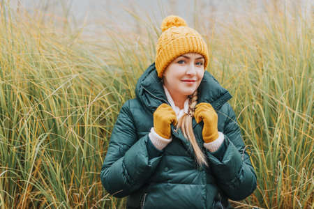 Autumn portrait of young woman wearing green jacket and set of yellow hat and glovesの写真素材