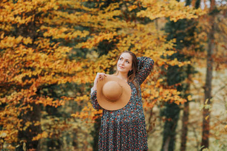 Outdoor portrait of beautiful woman enjoying autumn forest on a nice warm dayの写真素材