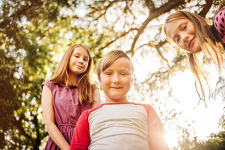 Group of 3 funny kids playing together outside on a  sunny day.