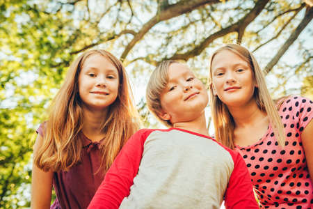Group of 3 funny kids playing together outside on a  sunny day.の写真素材