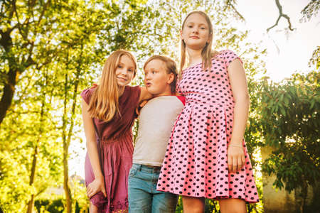 Group of 3 funny kids playing together outside on a  sunny day.