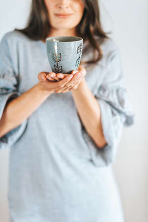 Female hands holding grey cup of olffee or teaの写真素材