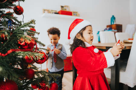 Group of two little children playing with Christmas tree at homeの写真素材
