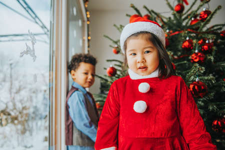 Group of two little children playing with Christmas tree at homeの写真素材