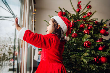 Cute toddler girl looking at the window at Christmas timeの写真素材