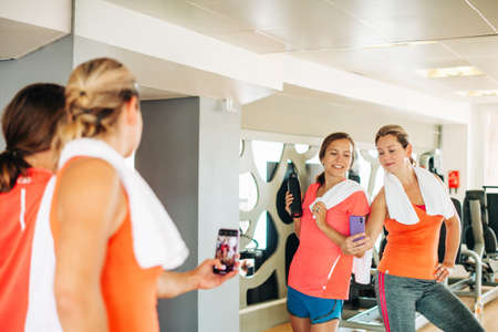 Two girls taking selfie with smartphone in gym