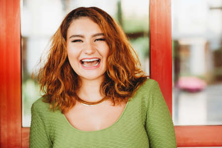 Outdoor portrait of happy laughing girl, wearing green top, golden necklaceの写真素材