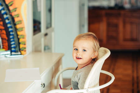 Cute toddler girl sitting at the desk, ready to drawの写真素材