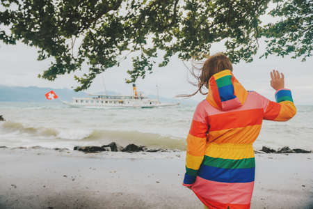 Child waving to sream boat with swiss flag, image taken on lake Geneva, Lausanne, Switzerlandの写真素材
