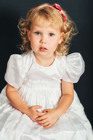 Studio shot of adorable 3 year old toddler girl wearing white occasion dressの写真素材