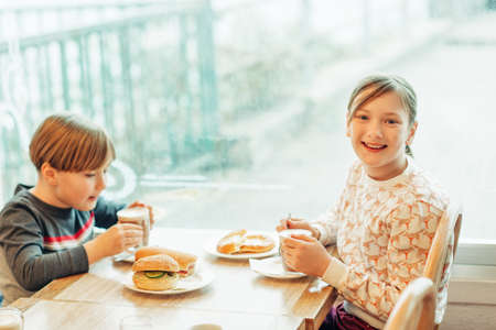 Two funny kids drinking hot chocolate in cafe on a rainy dayの写真素材