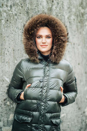 Winter portrait of beautiful woman with dark makeup, wearing warm jacket with fur hoodの写真素材
