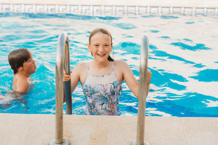 Two funny kids playing in the pool, brother and sister spending time togetherの写真素材