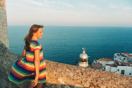 Little girl on the top of Peniscola, admiring amazing summer sunset, travel with children, wearing...
