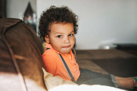 Portrait of adorable african kid boy resting on a couch