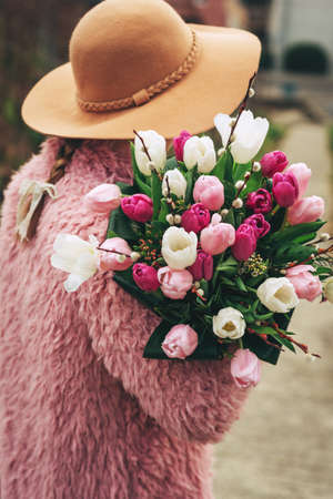 Close up image of beautiful tulips bouquet holding by young girl, back view