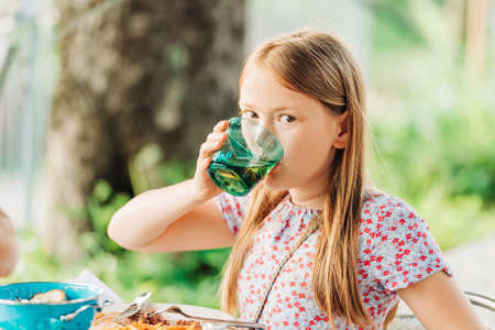 Little girl eating dinner on a terrace in outdoor restaurantの写真素材