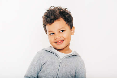 Studio shot of handsome african toddler boy wearing grey hoody, posing on white backgroundの写真素材