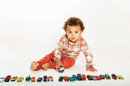 Studio shot of adorable african 1 year old baby boy playing with colorful mini carsの写真素材