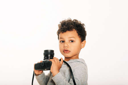 Studio shot of adorable african  toddler boy holding vintage camera