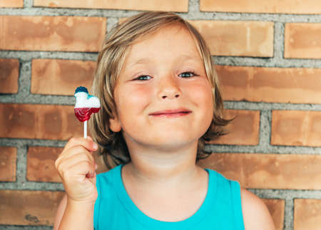 Young kid boy holding french flag colored lollipop candy