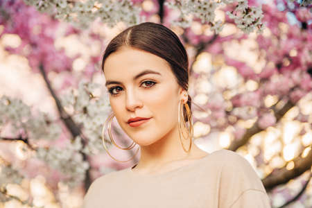 Outdoor portrait of beautiful 18-20 year old girl posing in blooming garden