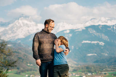 Happy laughing father and son hiking in mountains, active family time. Image taken in Valais, Switzerlandの写真素材
