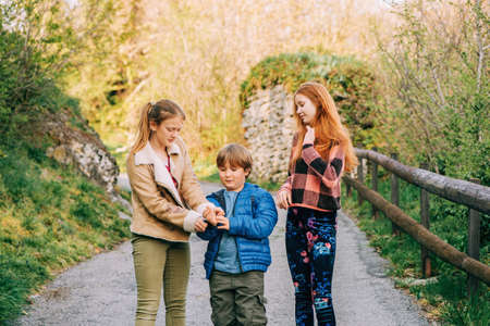 Group of 3 funny kids playing together in countryside, spring fashion for childrenの写真素材