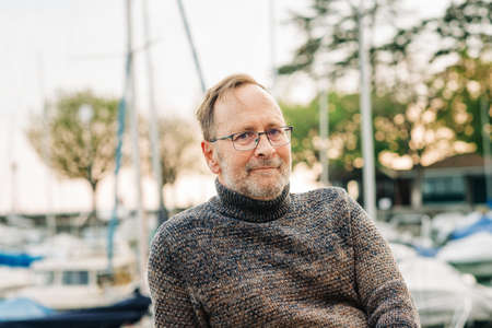 Outdoor portrait of 50 year old man wearing brown pullover and eyeglasses