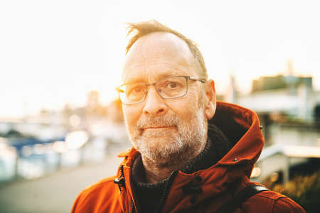 Outdoor portrait of middle age man wearing eyeglasses and orange winter jacketの写真素材