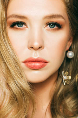 Close up portrait of beautiful young woman with blond hair and professional make up, posing on black backgroundの写真素材