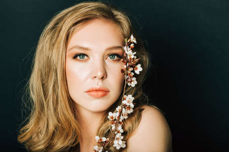 Close up portrait of beautiful young woman with blond hair and professional make up, posing on black...